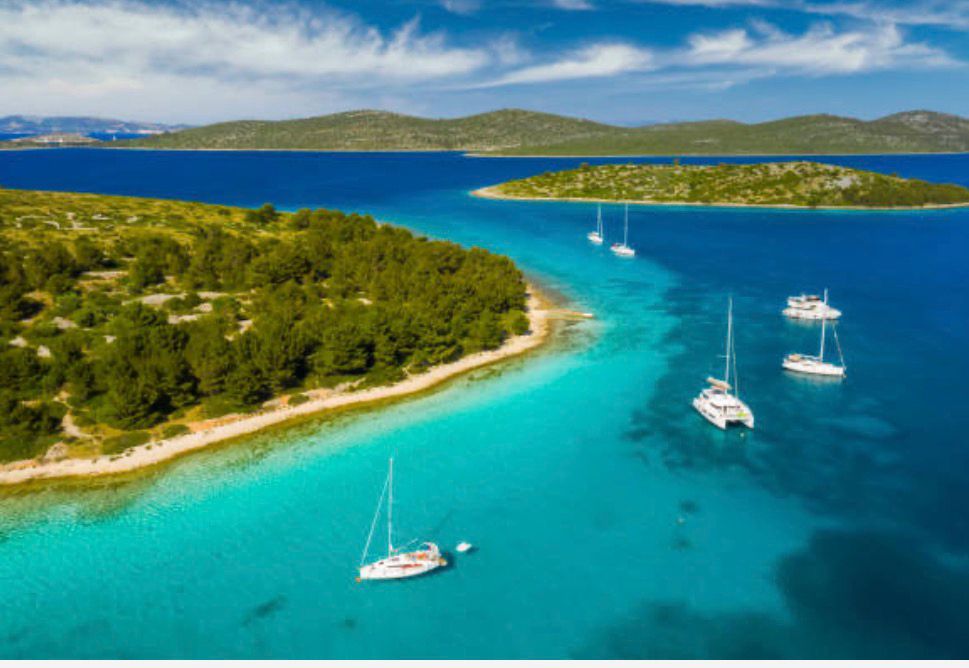 Yachts and a catamaran anchored in a turquoise Adriatic cove