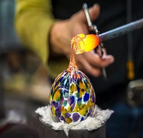 A finished piece of Murano glass in swirling millefiori colours, resting on white